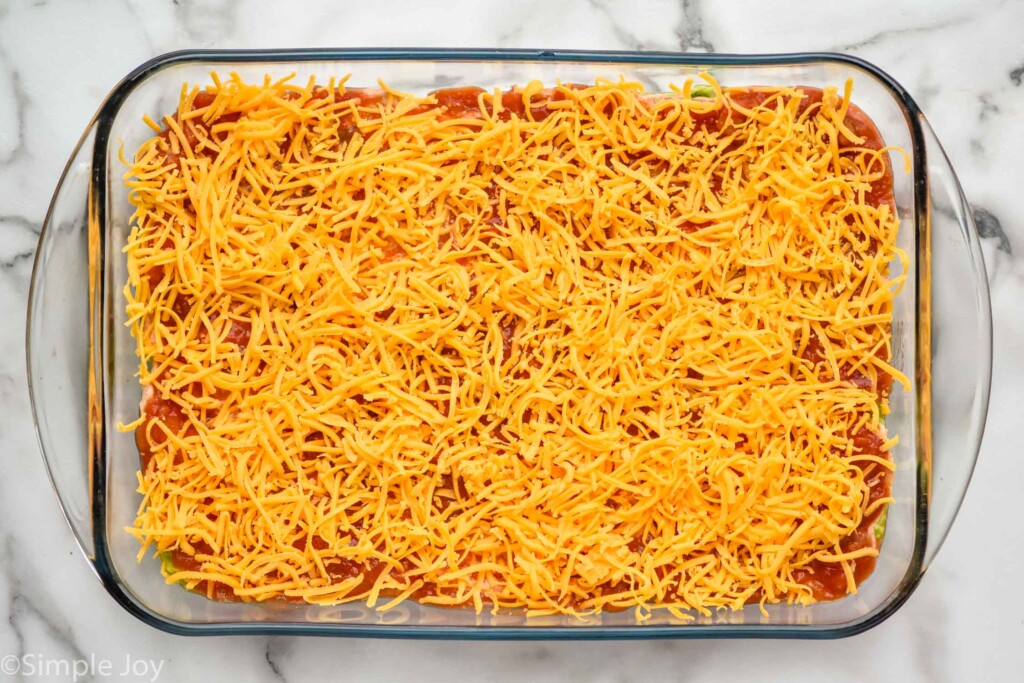 Overhead view of a baking dish of Seven layer dip recipe in process