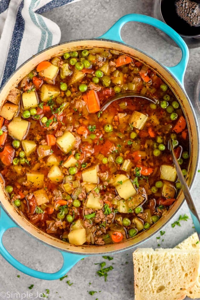 overhead of a large pot of Vegetable Beef Soup with a ladle for serving