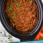 Pinterest graphic for Slow Cooker Taco Meat recipe. Image shows overhead view of a crockpot of Slow Cooker Taco Meat recipe garnished with cilantro. Text says, "crockpot taco meat simplejoy.com."