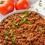 Pinterest graphic for Slow Cooker Taco Meat recipe. Text says, "slow cooker taco meat recipe simplejoy.com." Image shows a bowl of Slow Cooker Taco Meat garnished with cilantro, tomatoes beside.