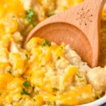 Close up of a wooden spoon in a casserole dish of Chicken and Rice Casserole recipe.