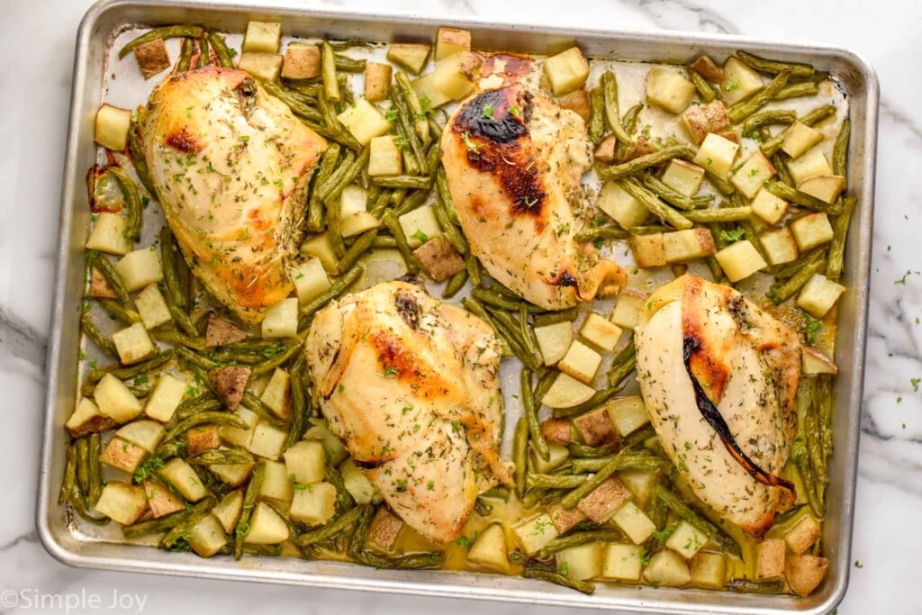 cooked sheet pan chicken on the sheet pan with potatoes and green beans