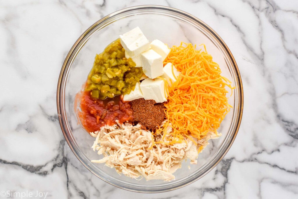 Overhead view of glass mixing bowl of ingredients for Chicken Taquitos recipe.