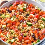 Bowl of chick pea salad garnished with parsley. Drinks beside.