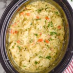 Overhead view of crock pot of Crockpot Chicken and Dumplings recipe with salad beside