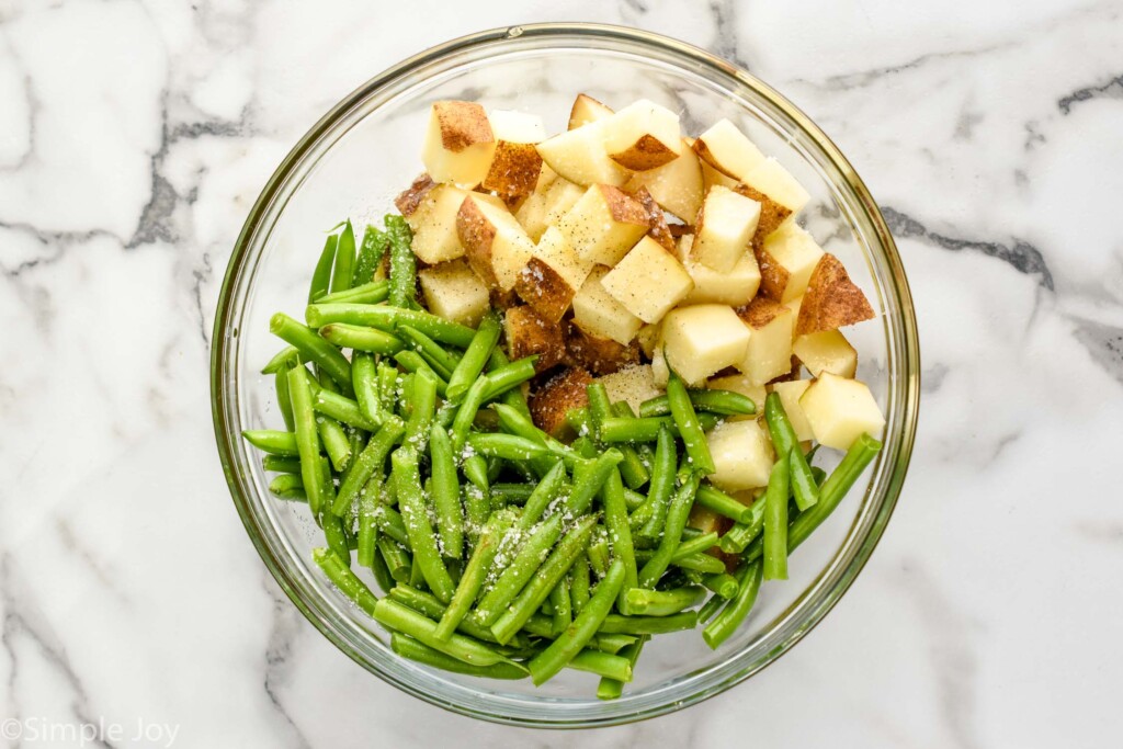 overhead of potatoes and green beans in a bowl with seasonings