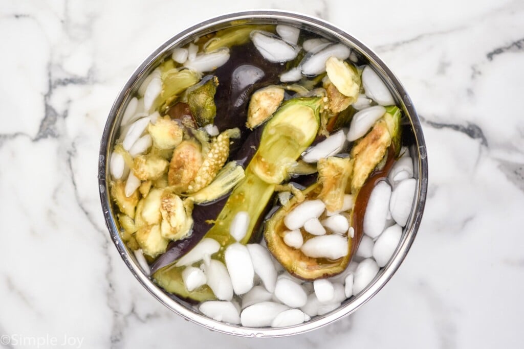 overhead of large bowl of cooked eggplant with water and ice to make Stuffed Eggplant