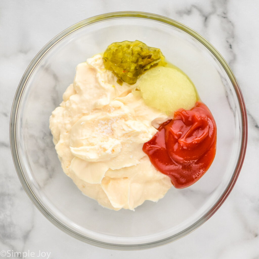 Overhead view of a glass mixing bowl with ingredients for Thousand Island Dressing recipe before mixing.