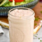 Jar of Thousand Island Dressing recipe with bowl of salad behind.