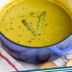 Pinterest graphic for Asparagus Soup recipe. Image shows a pot of Asparagus Soup garnished with two pieces of asparagus. Text says, "Asparagus Soup simplejoy.com."