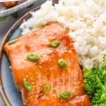 Pinterest graphic for Teriyaki Salmon recipe. Text says, "the best Teriyaki Salmon simplejoy.com." Image shows a plate of Teriyaki Salmon garnished with green onions and sesame seeds served with white rice and broccoli.