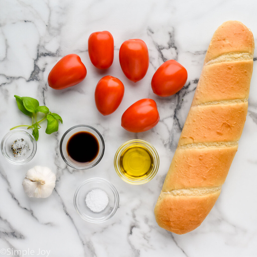 Overhead view of ingredients on countertop for Bruschetta recipe.