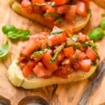 Bruschetta served on a wooden board garnished with basil leaves