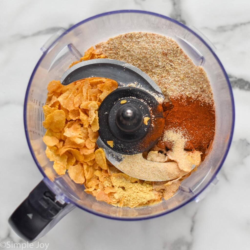 overhead of food processor with Baked Chicken Tenders breading ingredients