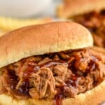 Side view of a Crock Pot Pulled Pork sandwich garnished with bbq sauce