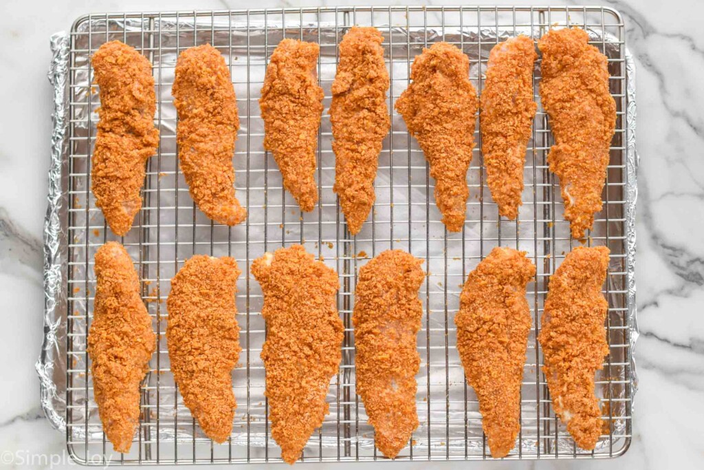 overhead of Baked Chicken Tenders on a wire cooling rack over a foil-lined baking sheet.