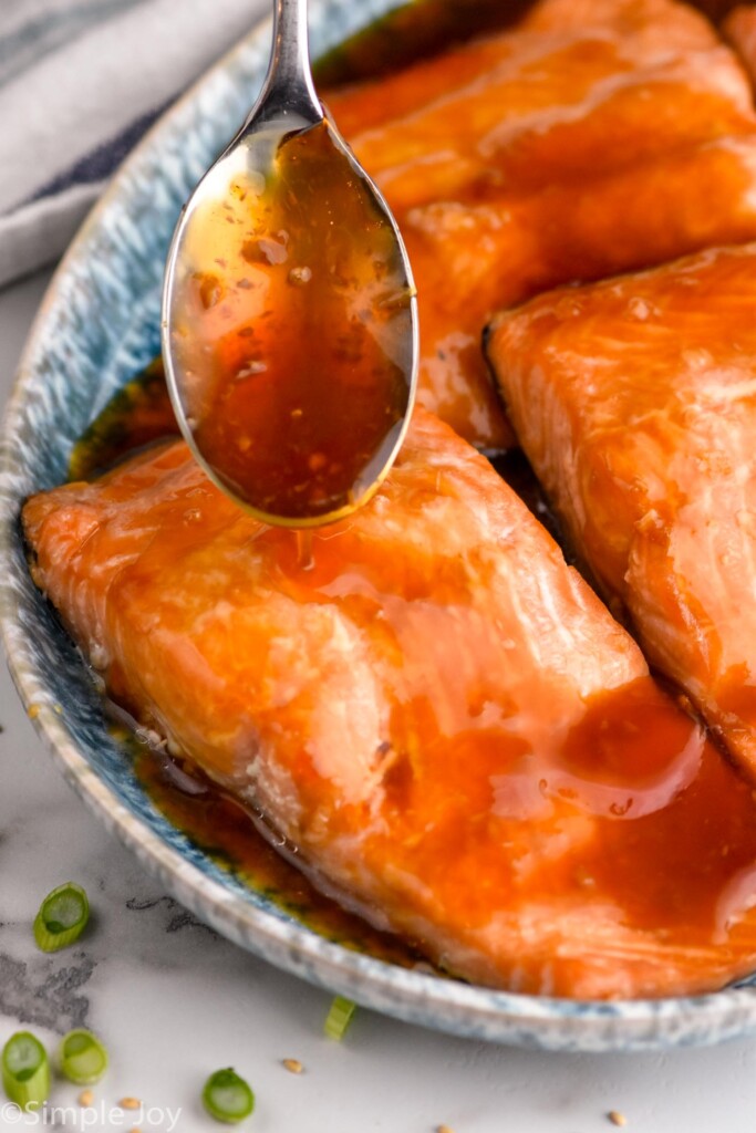 Close up of spoon of glaze being poured over salmon for Teriyaki Salmon recipe.