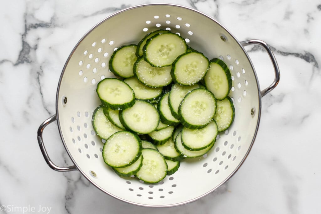 overhead of colander of cucumber slices with salt to make cucumber sandwich