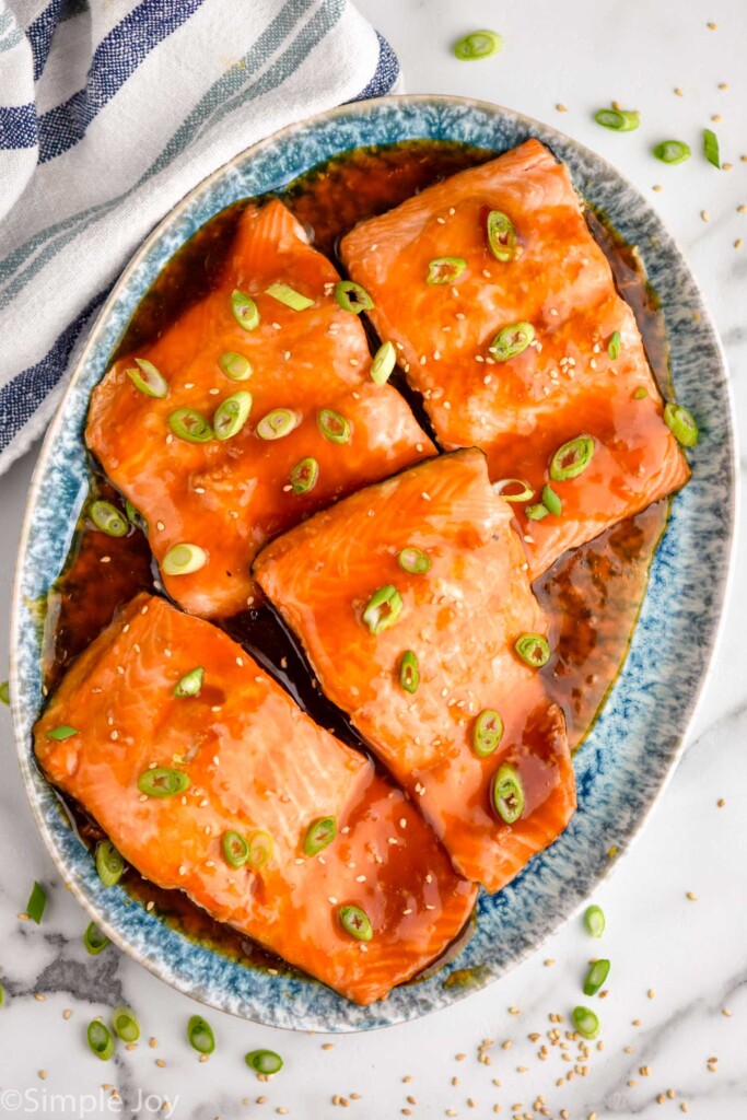 Overhead view of Teriyaki Salmon on a platter garnished with green onions and sesame seeds.