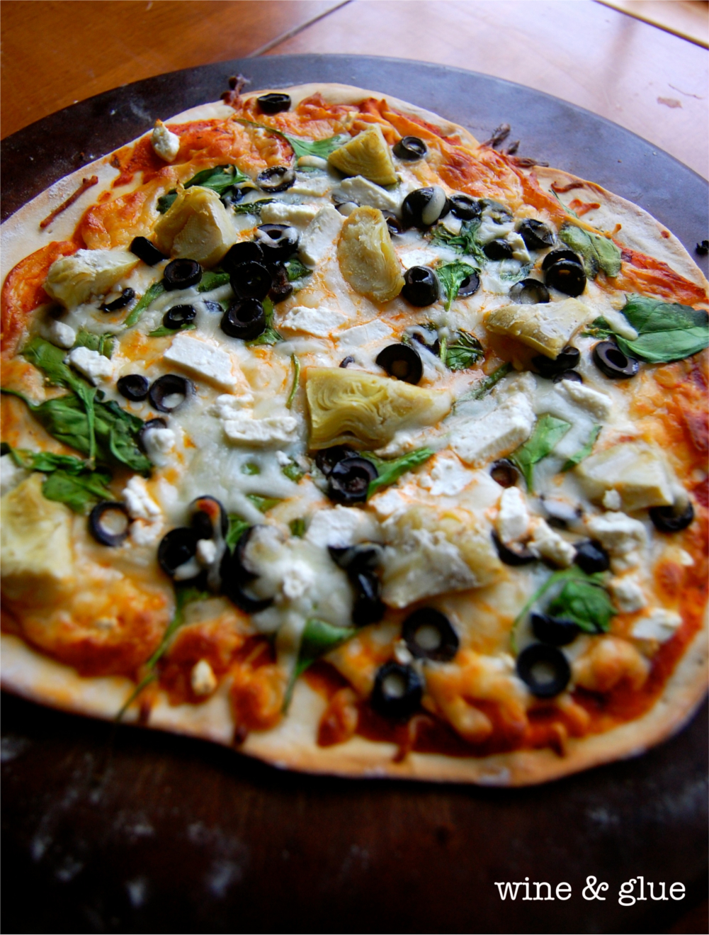 The Spinach Artichoke Pizza that is fully cooked with a brown crust and melted cheese toppings. 