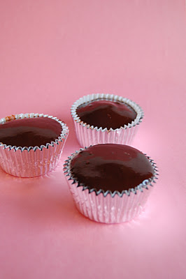 Three cupcakes in tin foil looking liners and all frosted with chocolate