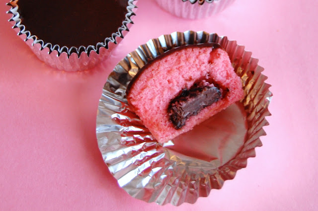 A cut in half pink cupcake that exposes the Dove Chocolate middle 